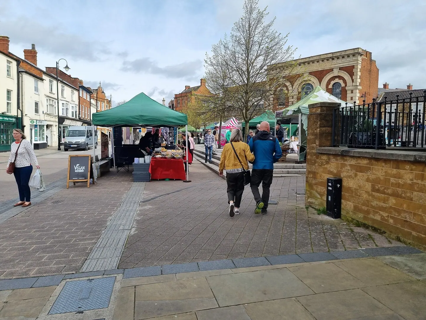 The vegan market on Kettering Market Place, with shoppers walking through