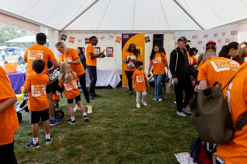 Families and volunteers gather inside the Children with Cancer UK tent at a previous Westminster Mile.