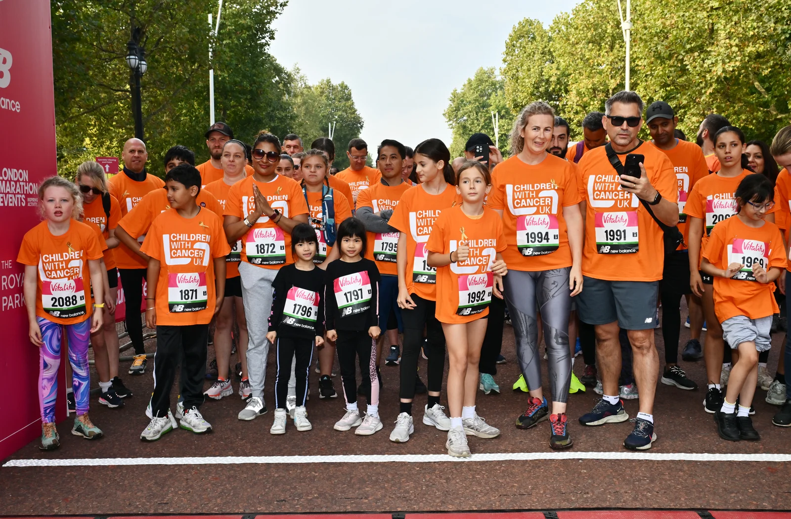 Children with Cancer UK supporters gather at the start line wearing orange charity shirts at a previous Westminster Mile.